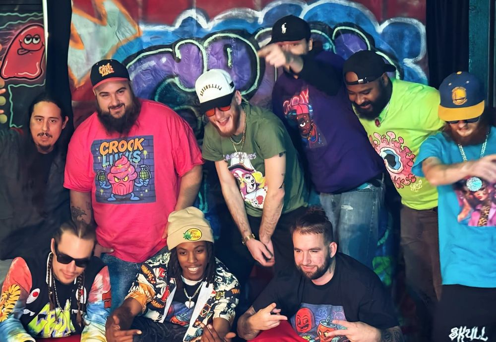 Group wearing Crook Lives shirts in front of a graffiti mural