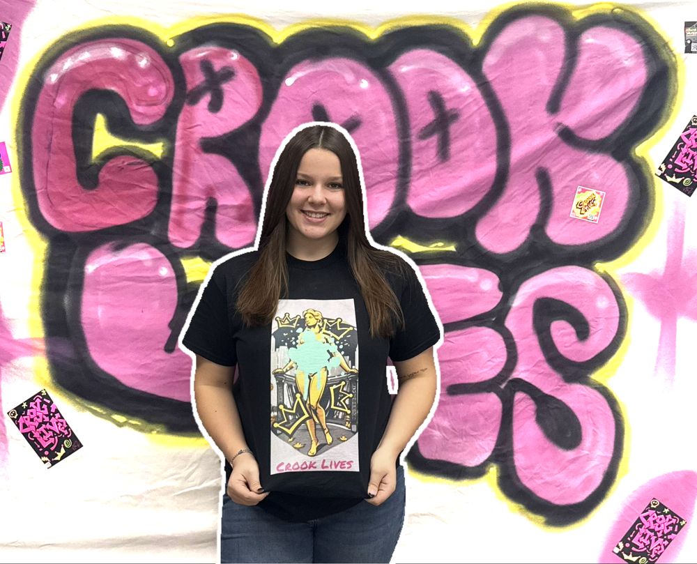 Crook Lives tee worn in front of a purple bubble-letter graffiti mural